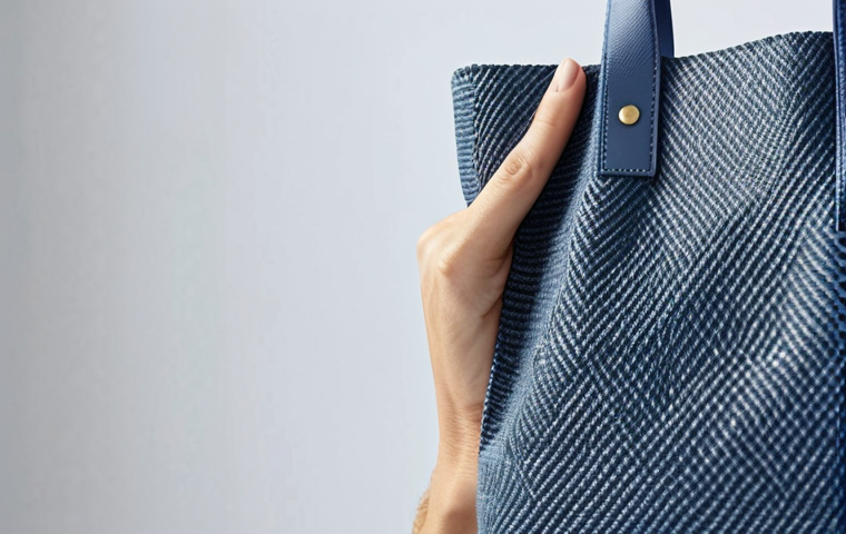 지속가능한 악세서리의 생산 과정 - Recycled Materials**
A stylish tote bag crafted from recycled PET bottles, displayed on a bright, m...