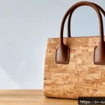 소재별 지속가능한 악세서리 특징 - A stylish eco-friendly handbag crafted from natural cork material, displayed on a rustic wooden tabl...